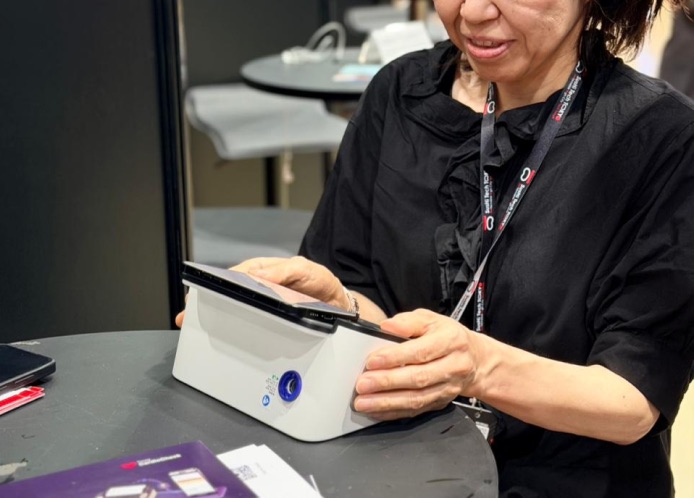 A Tricog team member demonstrating the OMRON cardiac screening device at an event
