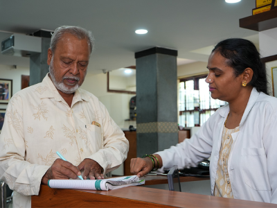 A patient checking in with a clinician at a front desk