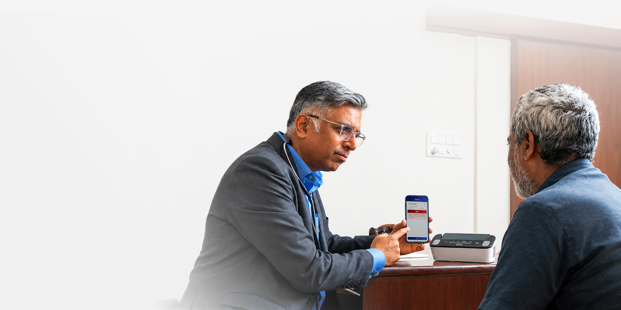 A doctor and a patient in consultation, reviewing a single-lead ECG on a Tricog CardioCheck device.
